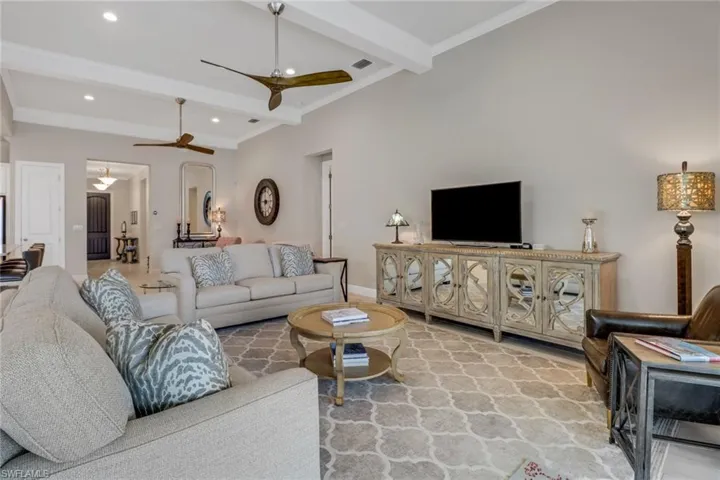 Living room featuring crown molding, beamed ceiling, and ceiling fans