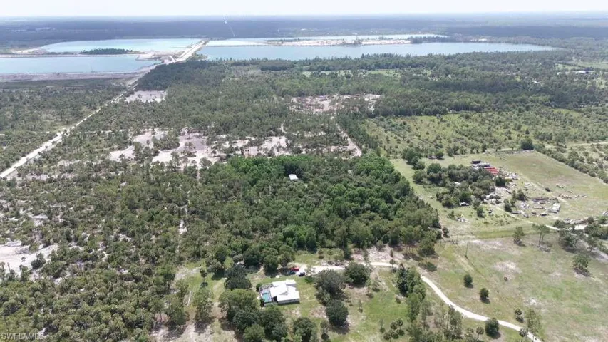 Expansive property featuring diverse terrain including wooded areas, open fields, and distant water bodies