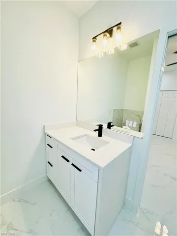 Bathroom with vanity, visible vents, marble finish floor, and baseboards