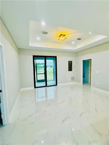 Spare room with a raised ceiling, baseboards, and visible vents