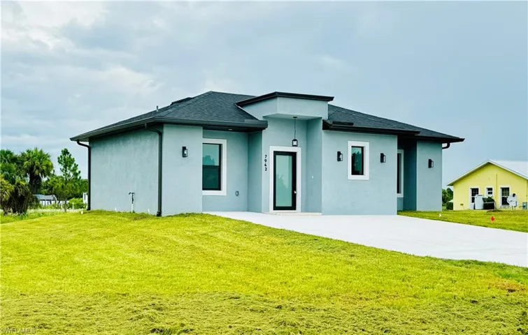View of front of house with a front yard, driveway, and stucco siding