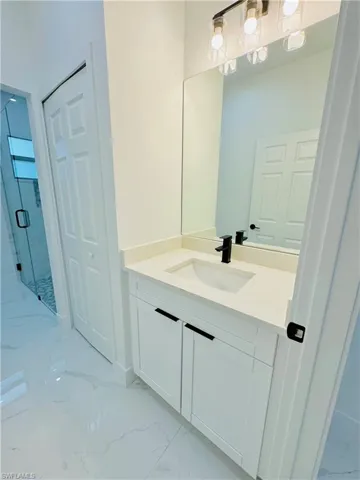 Bathroom with vanity, marble finish floor, and a stall shower