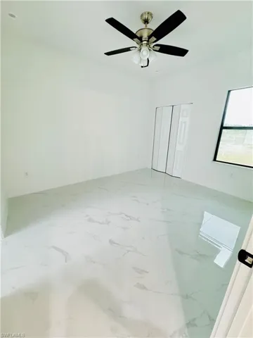 Spare room with marble finish floor and ceiling fan