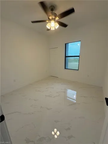 Unfurnished room with ceiling fan, marble finish floor, and baseboards