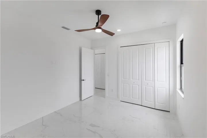 Unfurnished bedroom with light marble finish floors, a closet, a ceiling fan, and recessed lighting
