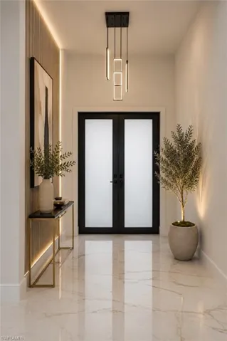 Polished marble-look flooring, modern linear pendant lighting, black double doors with frosted glass, wall paneling with integrated lighting, and a gold-finish console table
