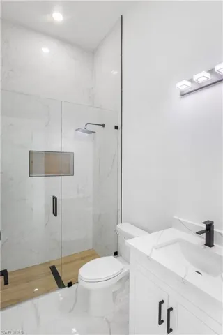 Bathroom with a marble finish shower, vanity, and marble finish flooring