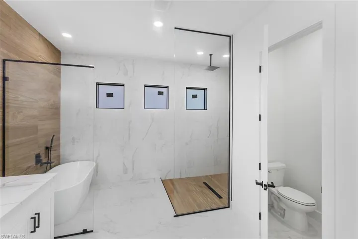 Full bath with a marble finish shower, a soaking tub, marble tiled flooring, vanity, and recessed lighting
