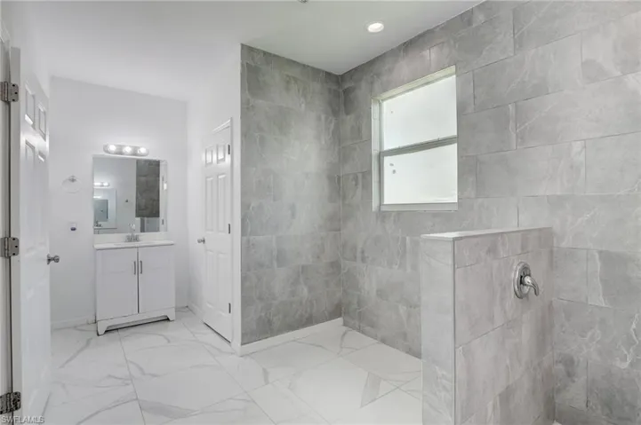 Bathroom featuring tile floors, large vanity, and a tile shower