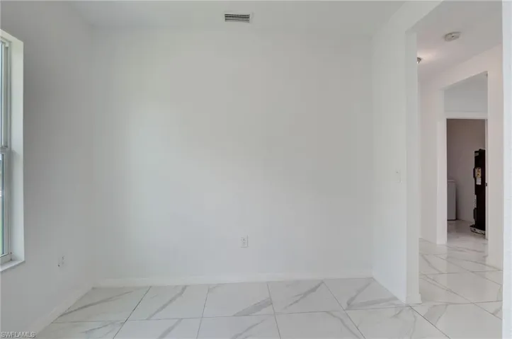 Clothes washing area featuring washer and dryer, water heater, and light tile floors