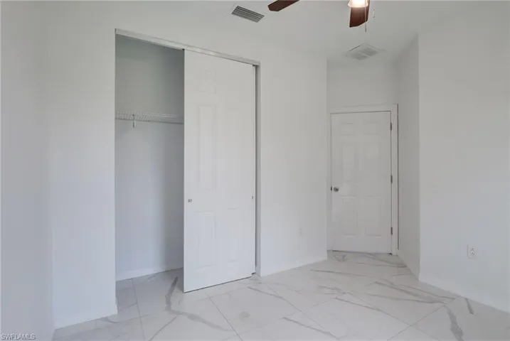 Unfurnished bedroom featuring a closet, ceiling fan, and light tile floors