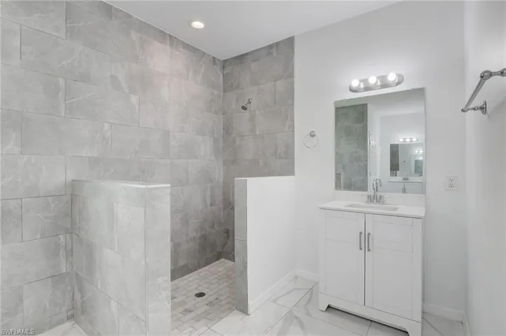 Bathroom featuring tile floors, large vanity, and a tile shower