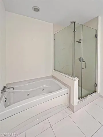 Bathroom with a shower stall, a jetted tub, and tile patterned floors