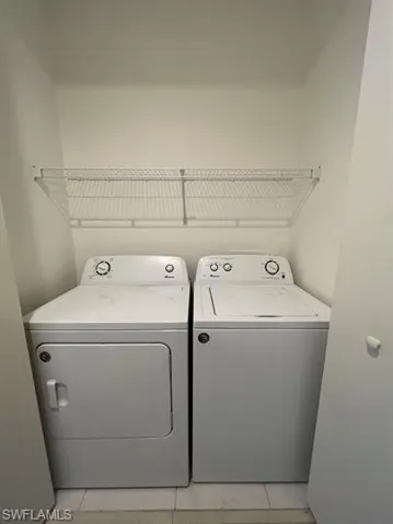 Laundry area featuring washing machine and clothes dryer and light tile patterned floors