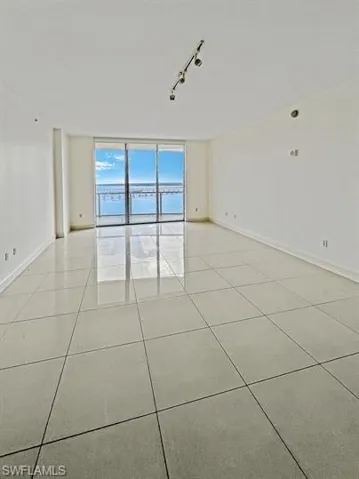 Unfurnished room with track lighting, light tile patterned flooring, and expansive windows