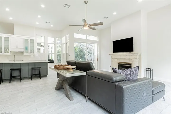 Living room with recessed lighting, a high end fireplace, ceiling fan, and a high ceiling