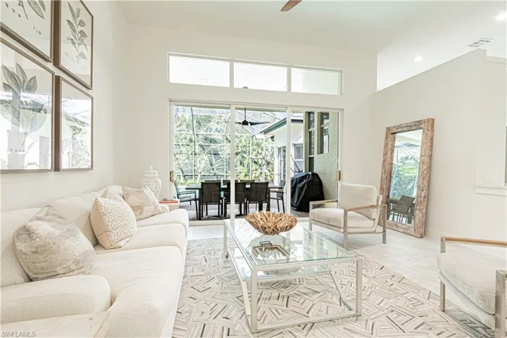 Living area with a sunroom, a ceiling fan, a high ceiling, and plenty of natural light