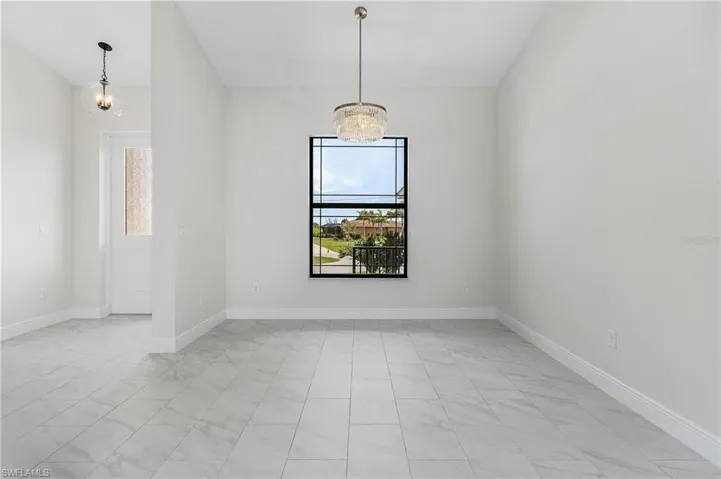 Unfurnished room featuring light tile patterned flooring and a notable chandelier