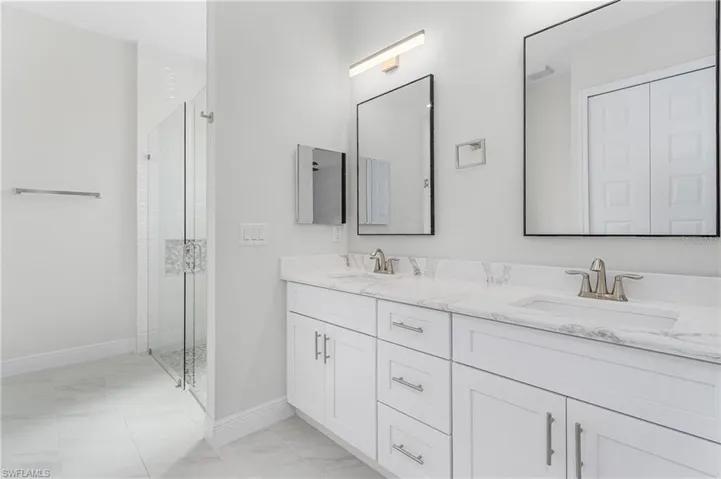 Bathroom featuring double vanity, tile patterned flooring, and a shower with door
