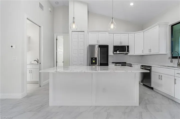 Kitchen featuring light tile patterned flooring, a kitchen island, and appliances with stainless steel finishes