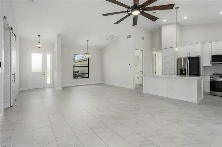 Unfurnished living room featuring light tile patterned floors, ceiling fan, and high vaulted ceiling