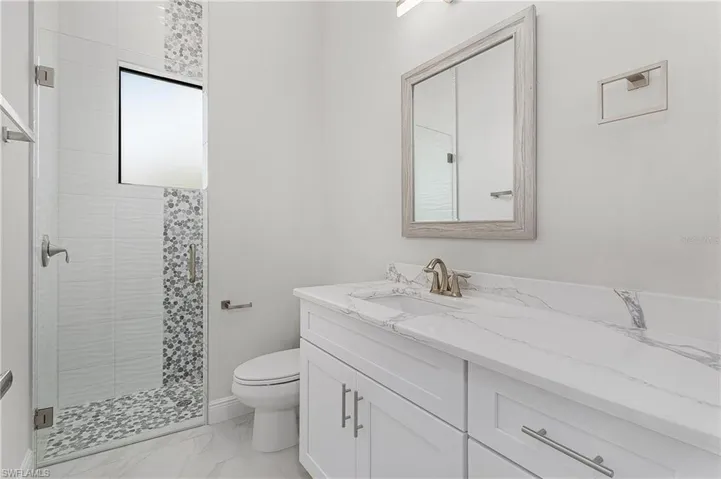 Bathroom with tile patterned floors, toilet, vanity, and a tile shower