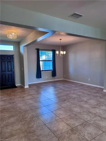 Foyer with light tile patterned floors and a chandelier