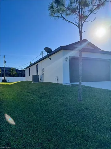View of side of home featuring a garage, a yard, and central air condition unit