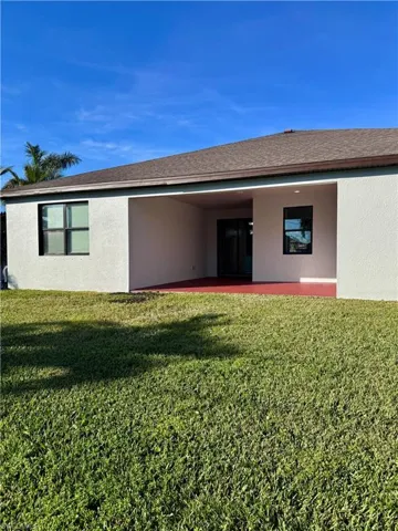 Rear view of house with a lawn and a patio
