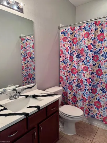 Bathroom with tile patterned flooring, vanity, toilet, and a shower with shower curtain