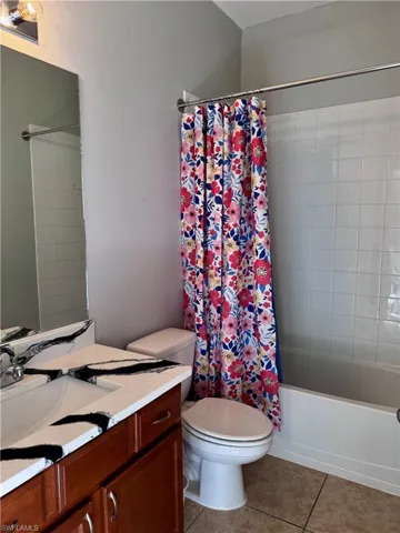 Full bathroom with vanity, tile patterned flooring, shower / bathtub combination with curtain, and toilet