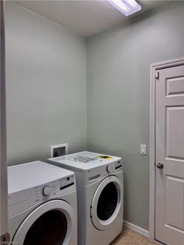 Washroom featuring washing machine and dryer and light tile patterned floors