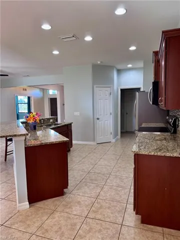 Kitchen with a kitchen bar, light tile patterned floors, a kitchen island, light stone counters, and stainless steel appliances