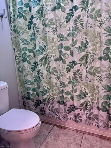 Bathroom featuring toilet, tile patterned floors, and walk in shower