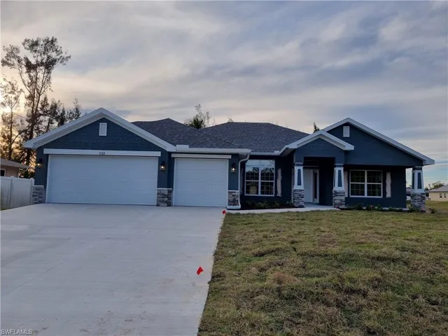 View of front of property featuring a lawn and a garage