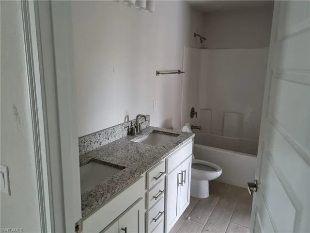 Full bathroom with wood-type flooring, vanity, toilet, and tub / shower combination