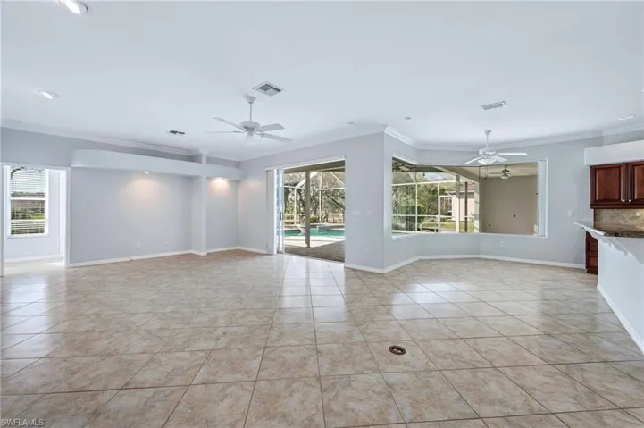 Unfurnished living room featuring light tile patterned floors, visible vents, a ceiling fan, and crown molding