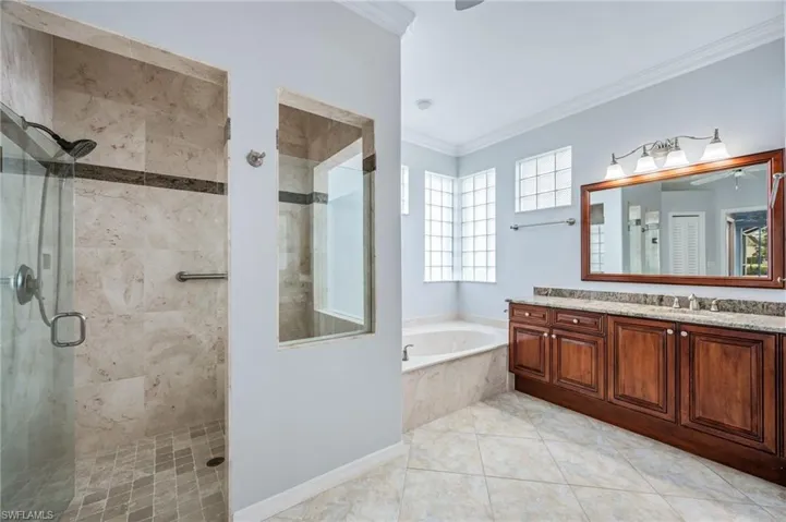 Bathroom with vanity, a garden tub, a stall shower, tile patterned flooring, and crown molding