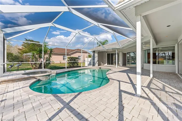 View of pool with glass enclosure, a patio area, and a pool with connected hot tub