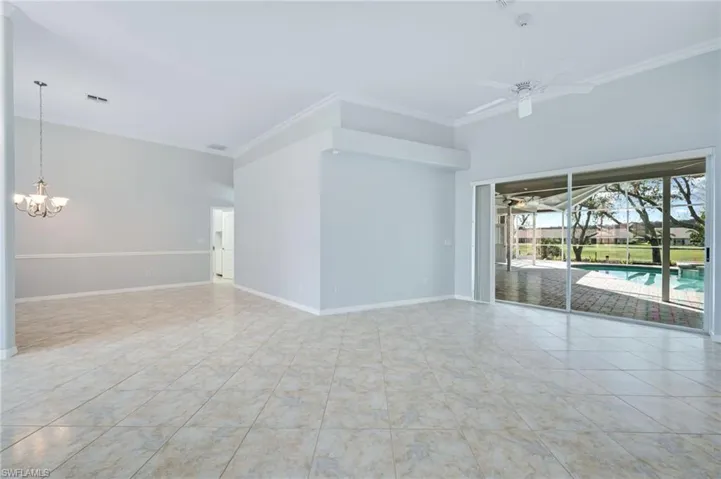 Tiled spare room with crown molding, ceiling fan with notable chandelier, baseboards, and visible vents