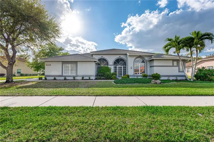 View of front of property with stucco siding, a tiled roof, and a front lawn