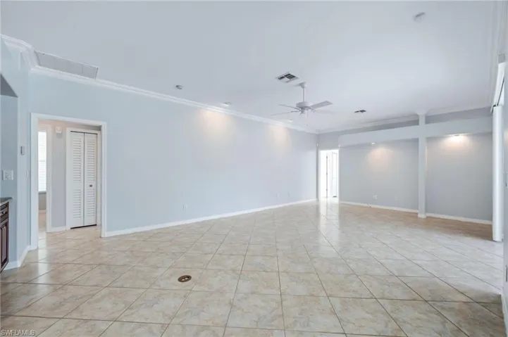 Empty room featuring visible vents, baseboards, ceiling fan, ornamental molding, and light tile patterned flooring