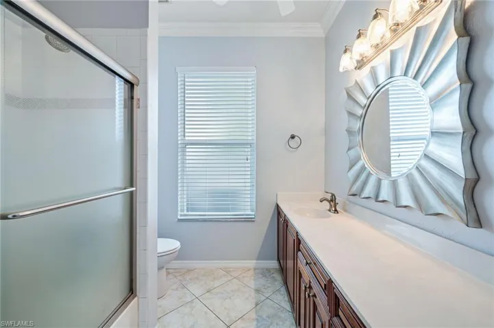 Full bathroom with a shower with shower door, baseboards, vanity, and crown molding