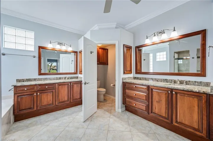 Full bath with a sink, a shower stall, two vanities, and ceiling fan