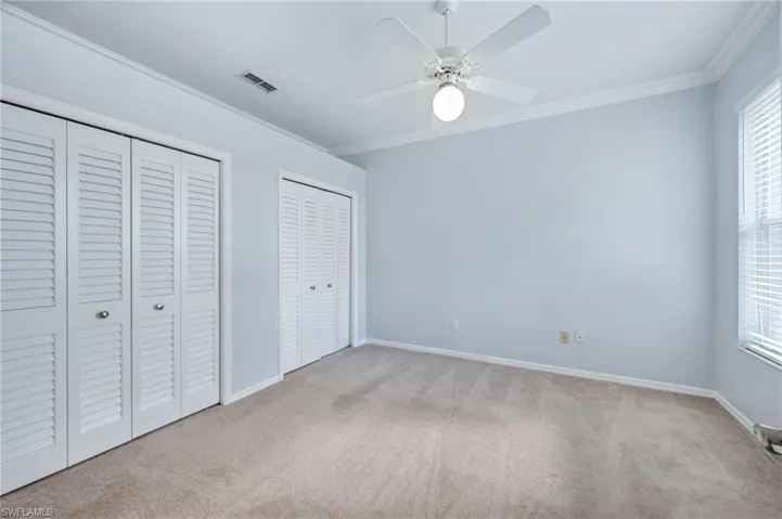 Unfurnished bedroom with multiple windows, multiple closets, ornamental molding, and carpet flooring
