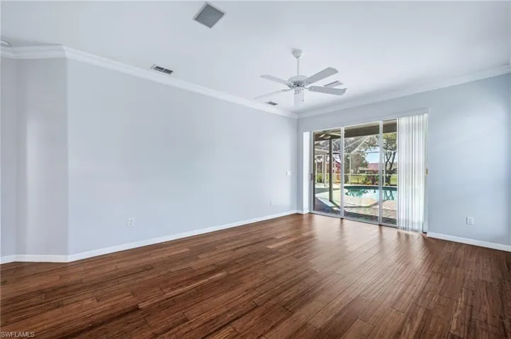Spare room featuring visible vents, a ceiling fan, dark wood finished floors, crown molding, and baseboards