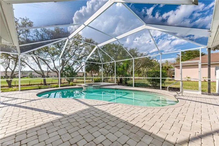 View of pool with glass enclosure, a patio, and a pool with connected hot tub