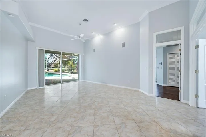 Spare room with crown molding, a ceiling fan, baseboards, and a towering ceiling