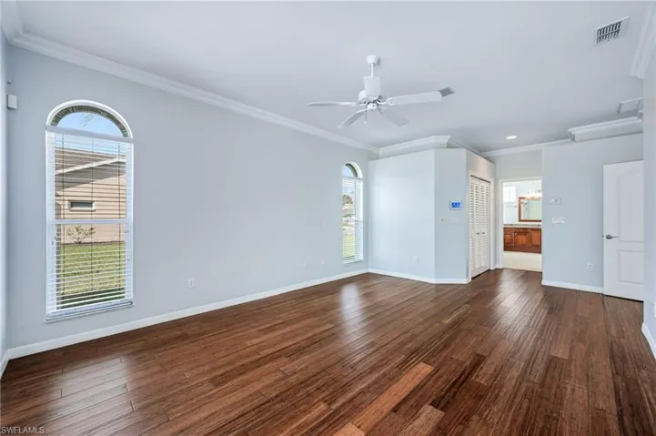 Spare room with visible vents, dark wood-type flooring, baseboards, and ornamental molding