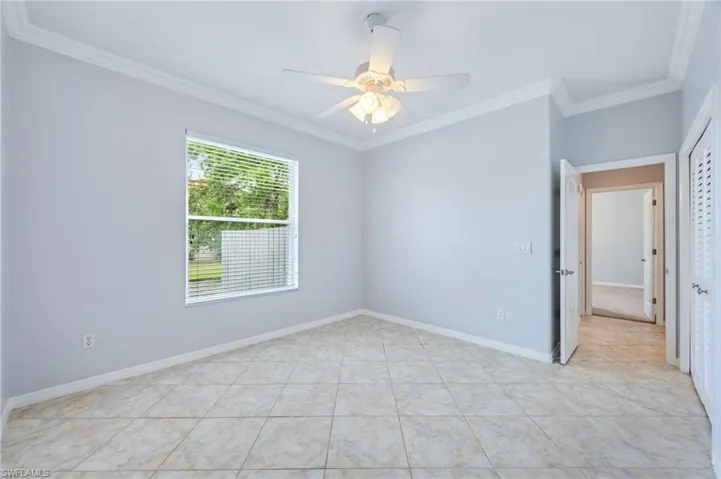 Spare room with ceiling fan, baseboards, ornamental molding, and light tile patterned floors